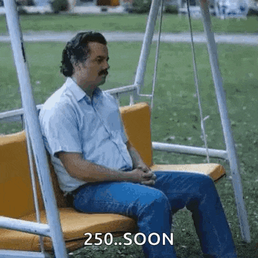 a man is sitting on a swing in a park with the words `` 250 soon '' written on it .