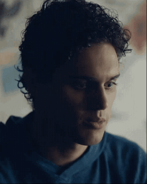 a close up of a young man 's face with curly hair