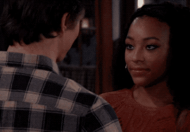 a man in a plaid shirt looks at a woman in a red top