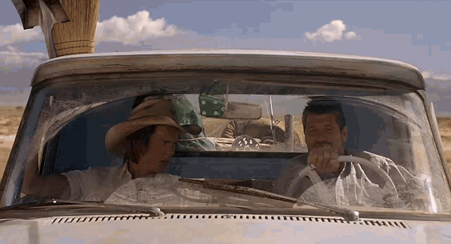 a man in a cowboy hat is sitting in the driver 's seat of a car