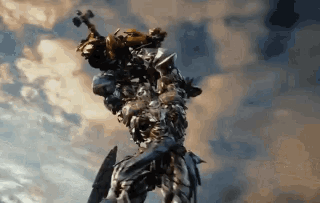 a statue of a robot holding a hammer and shield against a cloudy sky .