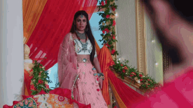 a woman in a pink and white dress is standing in front of a mirror in a room .