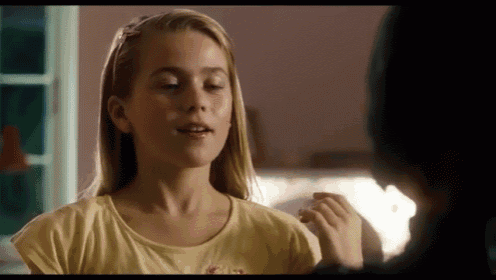 a girl wearing a yellow shirt with the word kiss on the front