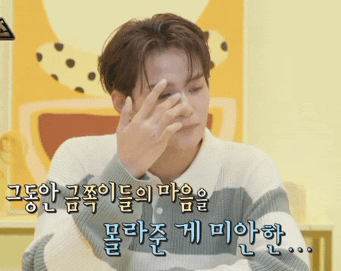 a man in a striped sweater is covering his face with his hand in korean