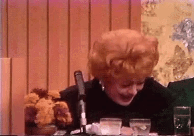 a woman with red hair is sitting at a table with a microphone in front of her .