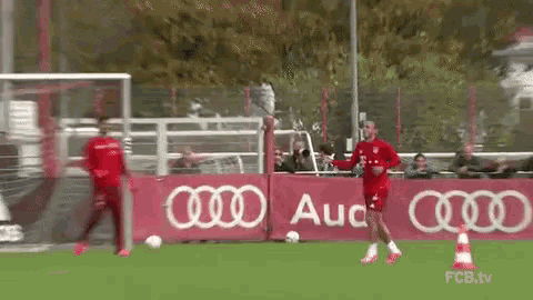 two soccer players are running on a field in front of an audi banner