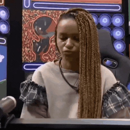 a woman with braids is sitting in front of a microphone in a room with speakers .