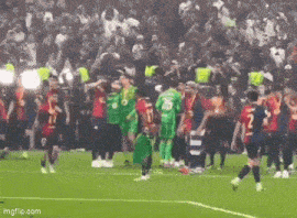 a group of soccer players standing on a soccer field .