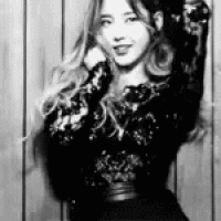a woman is standing in front of a wooden wall in a black and white photo .