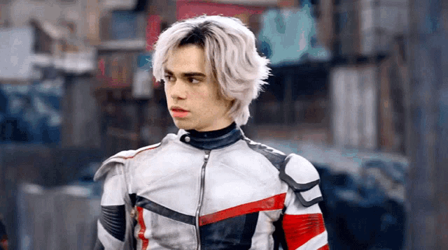 a young man with white hair is wearing a leather jacket and standing in a city street .