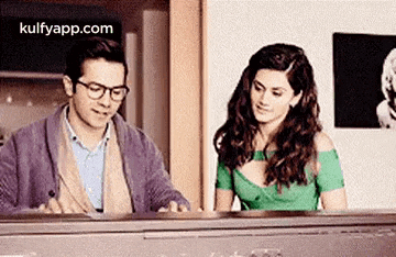 a man and a woman are sitting at a piano and looking at each other .