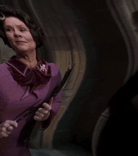 a woman in a purple sweater is holding a sword