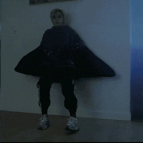 a person is standing in front of a wall wearing a hoodie and pants