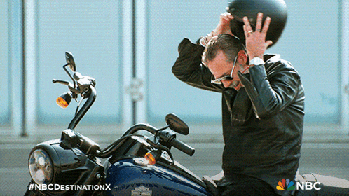 a man putting on a helmet while sitting on a motorcycle