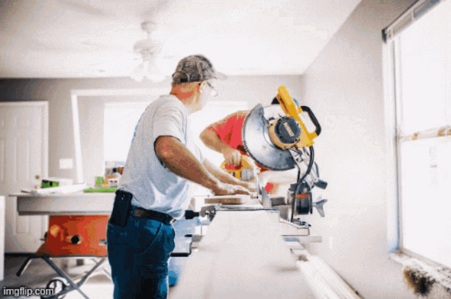 two men are using a circular saw in a room with imgflip.com at the bottom of the image