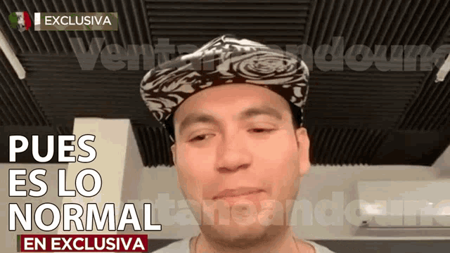 a man wearing a hat with the words " pues es lo normal " on the bottom