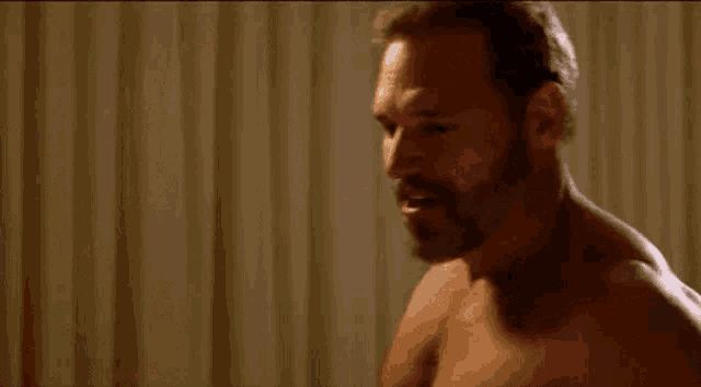 two men are having sex in a room without shirts on .