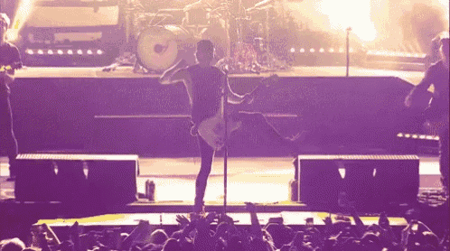 a man playing a guitar on a stage in front of a crowd .