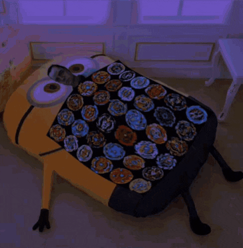 a bed made to look like a minion with a blanket filled with spinning tops on it .