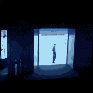 a blue screen shows a person in a chair in a dark room