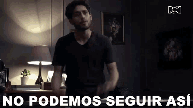 a man in a black shirt is standing in a dark room with the words " no podemos seguir así " behind him
