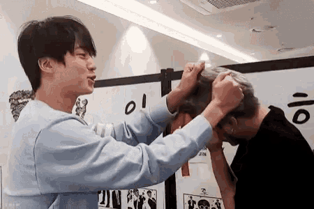 two men are standing next to each other and one of them is holding another man 's head