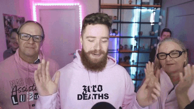 a man with a beard is wearing a pink hoodie that says zero deaths