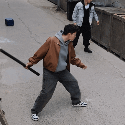 a man in a brown jacket is holding a black pole