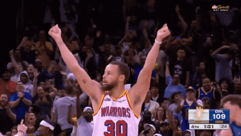 a warriors basketball player celebrates in front of the crowd