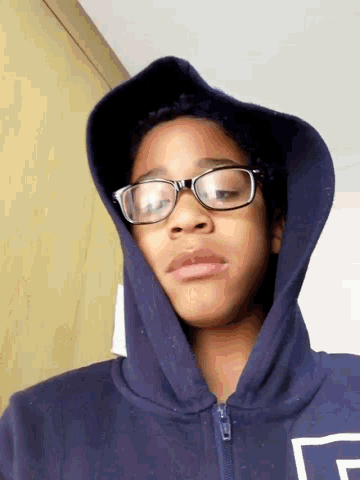 a person wearing glasses and a blue hoodie with the letter f on it