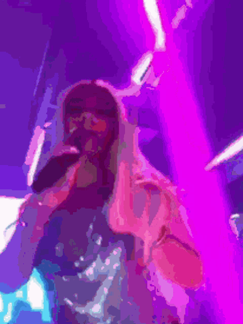 a woman singing into a microphone in front of a purple background