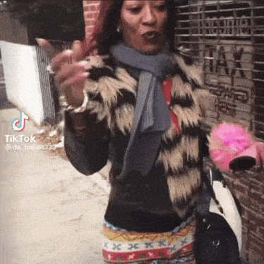 a woman wearing a fur coat and a scarf is standing in front of a building that says tax