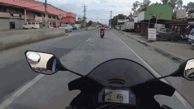 a person riding a motorcycle down a street with the number 66 on the speedometer