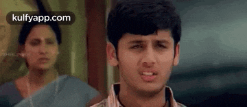 a young man is making a funny face while a woman looks on .