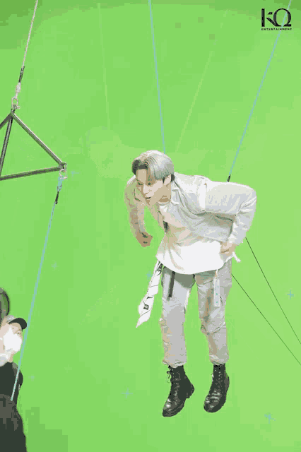 a man is hanging from a rope with the letter k on the bottom right