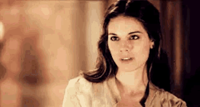 a woman in a white shirt is looking at the camera .