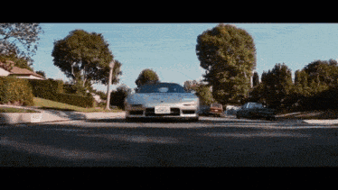 a silver sports car is driving down a street with a california license plate