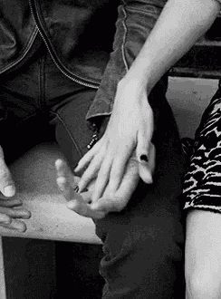 a man and woman are holding hands while sitting on a bench .