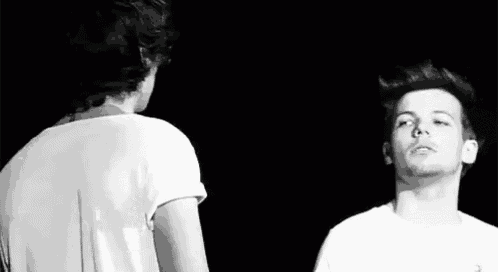 a black and white photo of two men standing next to each other in the dark .