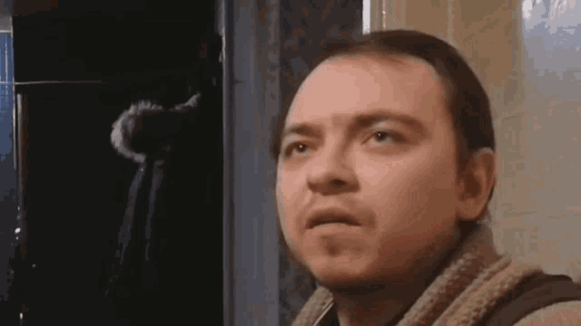 a man with a scarf around his neck is making a funny face in a bathroom .