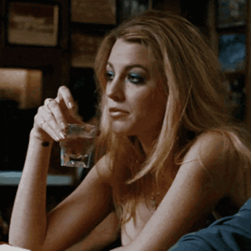 a woman sitting at a table holding a glass of water