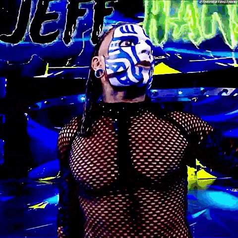 a wrestler with a blue and white mask on his face is standing in front of a green sign .