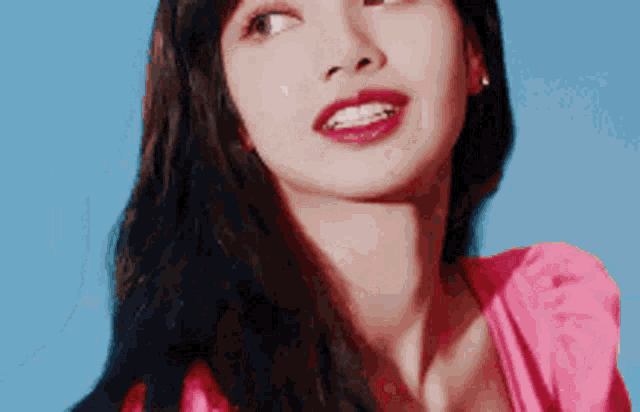 a close up of a woman 's face wearing a pink dress against a blue sky .