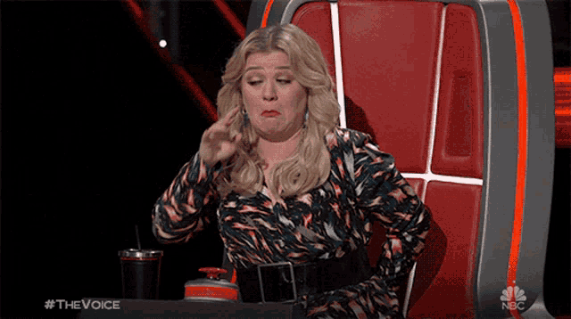a woman sitting in a chair with the word the voice on the bottom right
