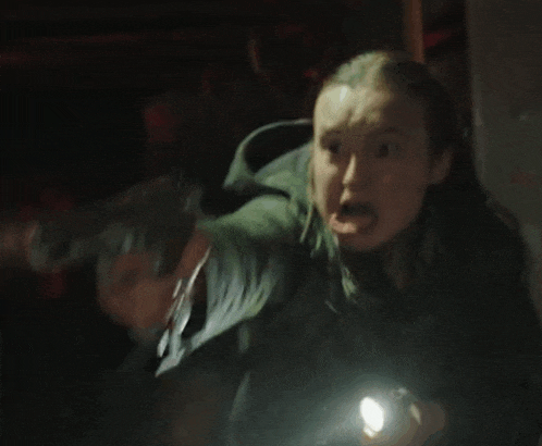 a woman is holding a flashlight in her hand in the dark and screaming .
