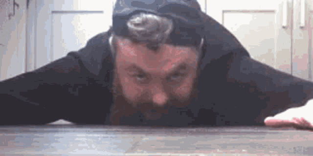 a man with a beard is laying on a wooden floor .