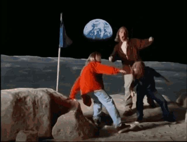 a group of people are standing on the moon with a flag in the background .