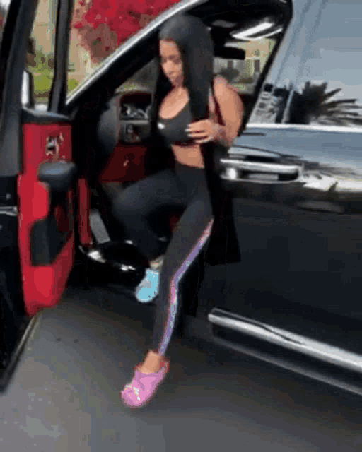 a woman wearing pink crocs is getting out of a black car