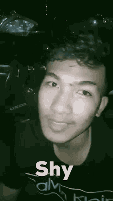 a young man is making a funny face in front of a car while wearing a black shirt .