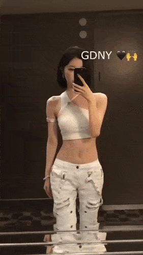 a woman taking a picture of herself in a mirror with gdny written on the bottom right